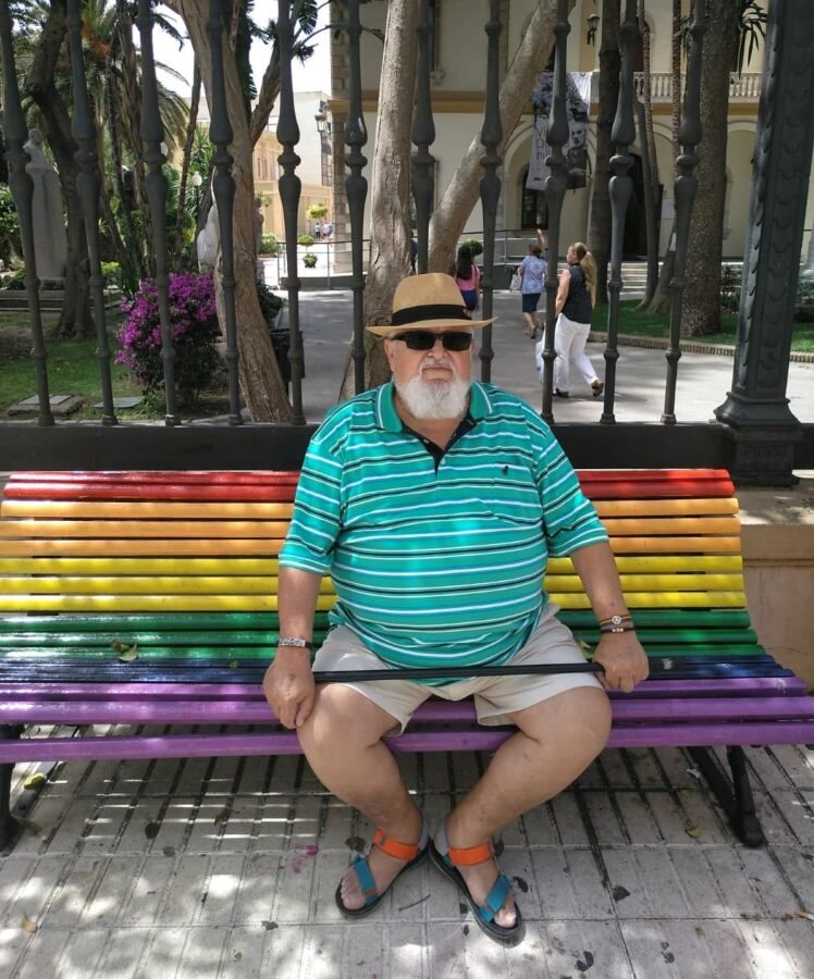 Emilio Isla en un banco con la bandera del orgullo.