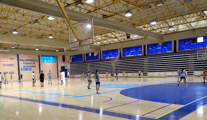 Un partido de baloncesto en la cancha del polideportivo municipal iluminada.