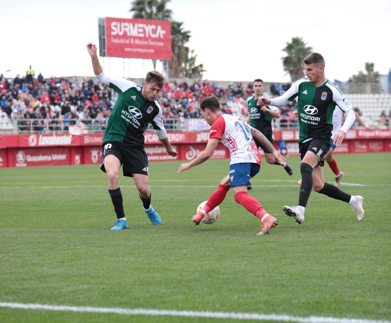 Álvaro Romero entre dos jugadores del Badajoz. Foto: Algeciras Club de Fútbol.