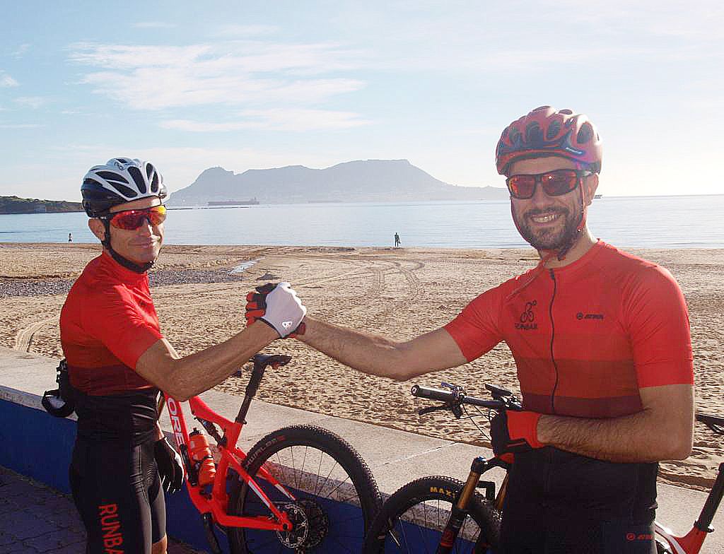 Los ciclistas Luis Mangas y Daniel Andrades, del CD Runbaik de Los Barrios, se estrechan la mano en Getares