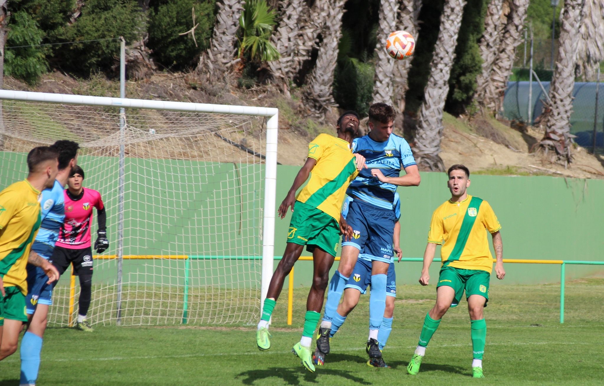 El jugador de la UD Los Barrios, Fraik, salta por el balón con un futbolista del Villafranco CF