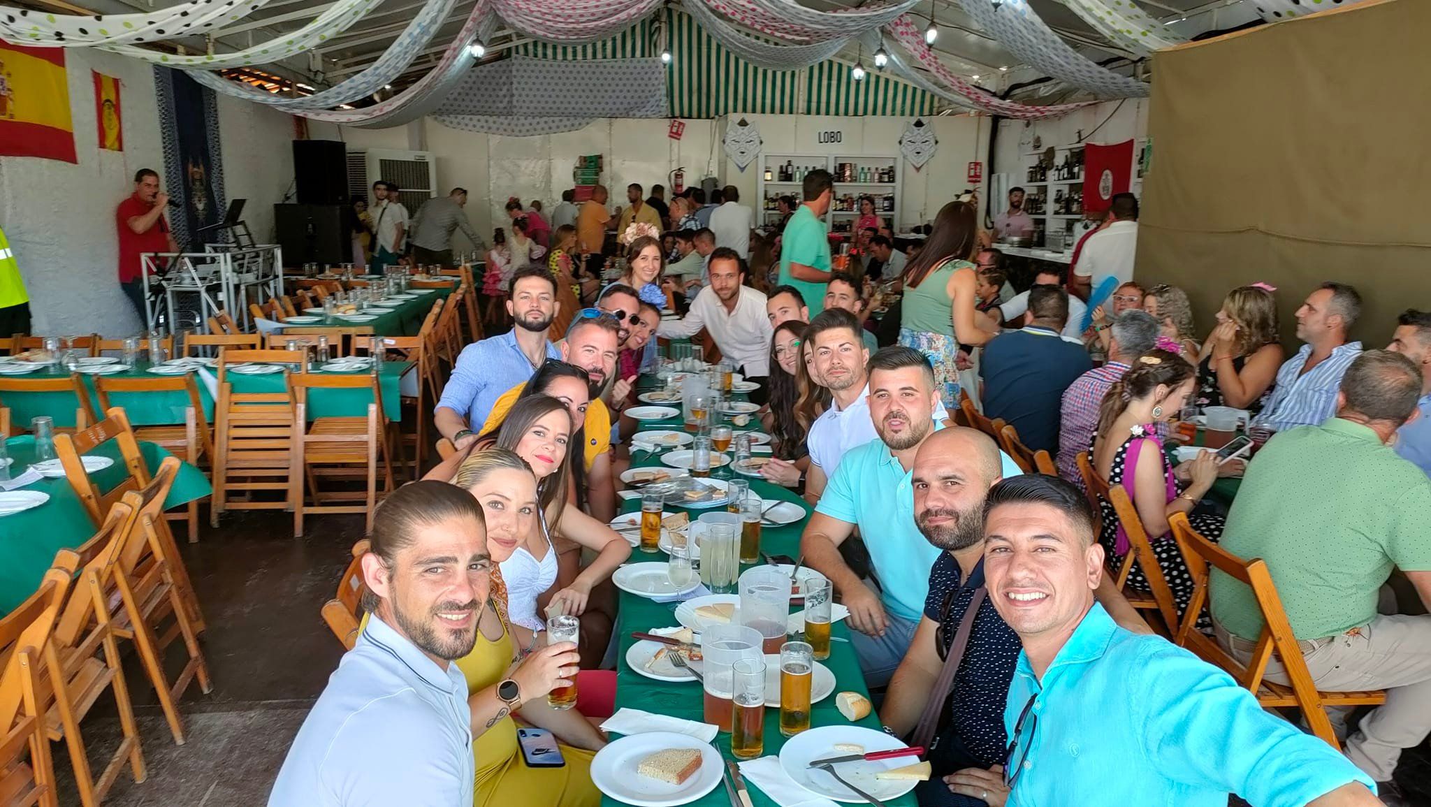 Un grupo de jóvenes almuerza en una caseta en la Feria Real de 2022.