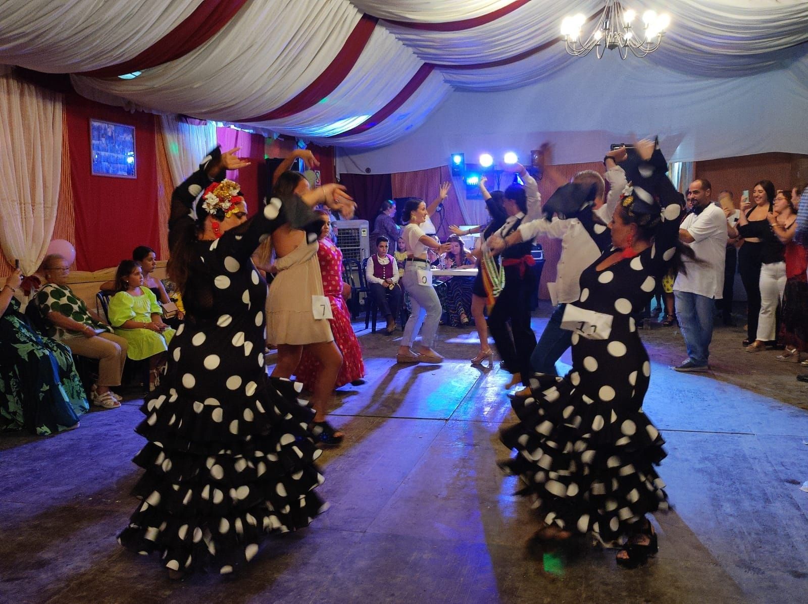 Las ocho tradiciones de la Feria de La Línea que no te debes perder. En esta imagen, dos mujeres bailando sevillana en una caseta de La Línea en la feria de 2022.