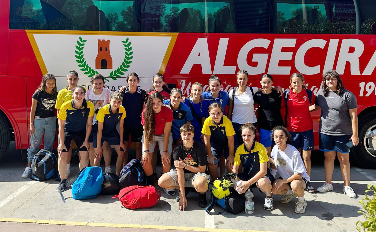 Las jugadoras del CD Algeciras posan delante del bus con el escudo del Algeciras CF que les ha trasladado a Cádiz