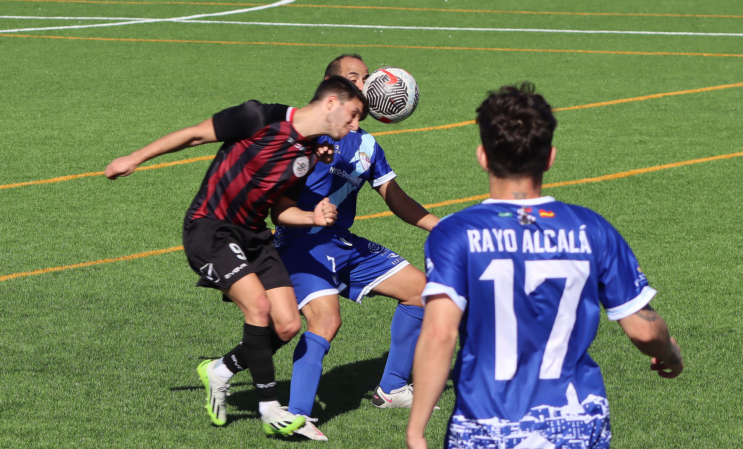 El jugador del CD La Rock Puente, David Borrego, mete la cabeza ante Javi, del CD Rayo Alcalá, ante la mirada de Galán (17)/Foto: Axel S.C.