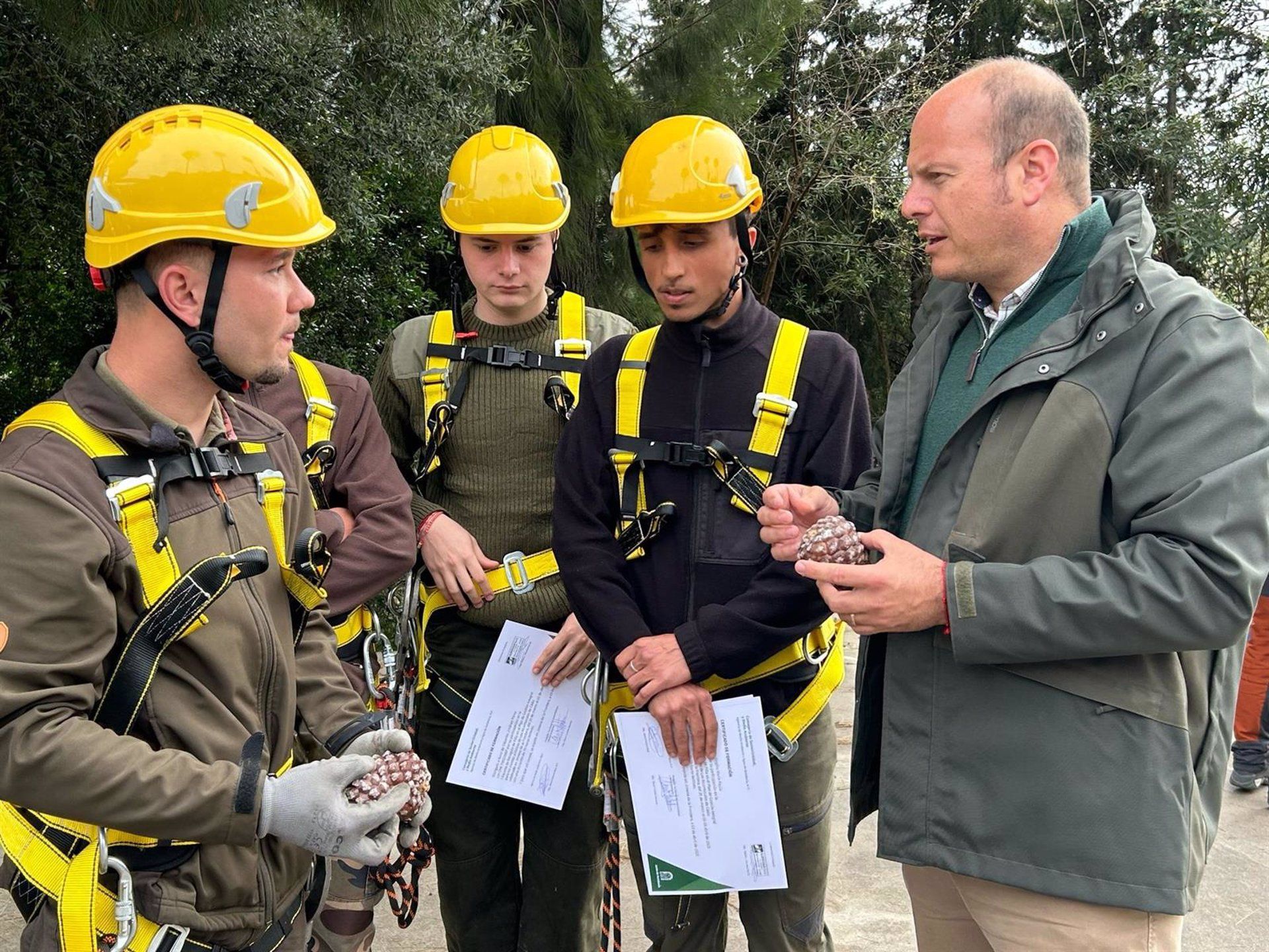 El delegado territorial de Sostenibilidad y Medio Ambiente en la provincia de Cádiz, Óscar Curtido, junto a alumnado de la primera promoción de la escuela de piñeros en los montes públicos de los Alcornocales