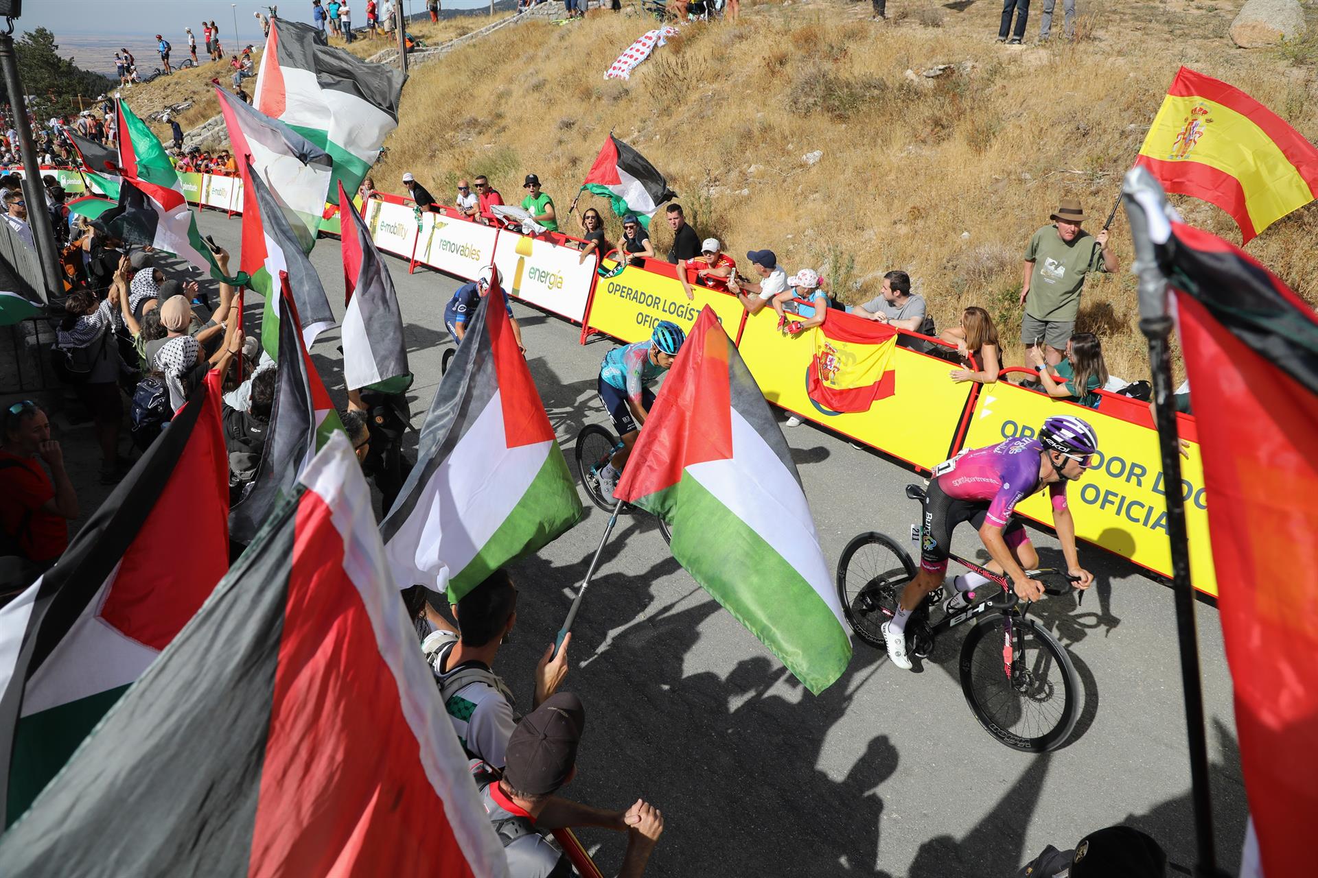 Varios ciclistas pasan por una zona con protestas propalestinas durante la 20ª etapa de la Vuelta Ciclista a España. - Rafael Bastante - Europa Press